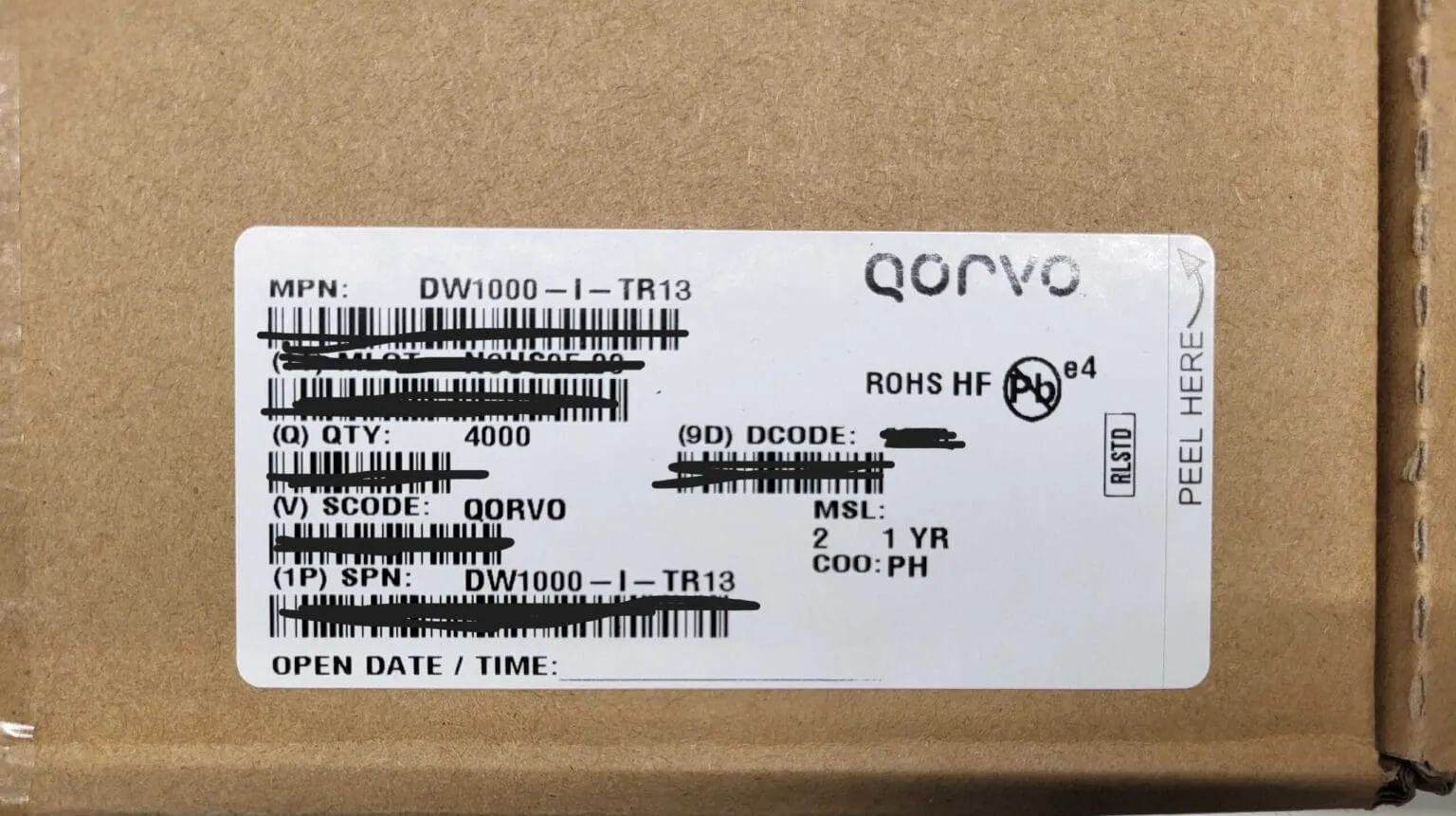 White label on a cardboard box reading DW1000-I-TR13, Qorvo, quantity 4000, with some barcode lines blacked out