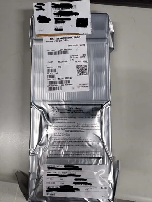 Silver moisture-barrier bag with an NXP Semiconductors label and caution notice, some label text blacked out
